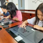 Student at QISS practicing Chinese calligraphy on a digital tablet